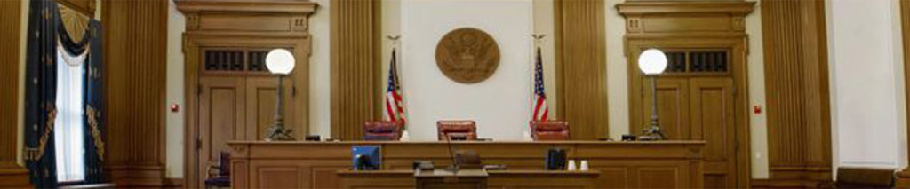 Empty courtroom with American flags and seal on the wall.