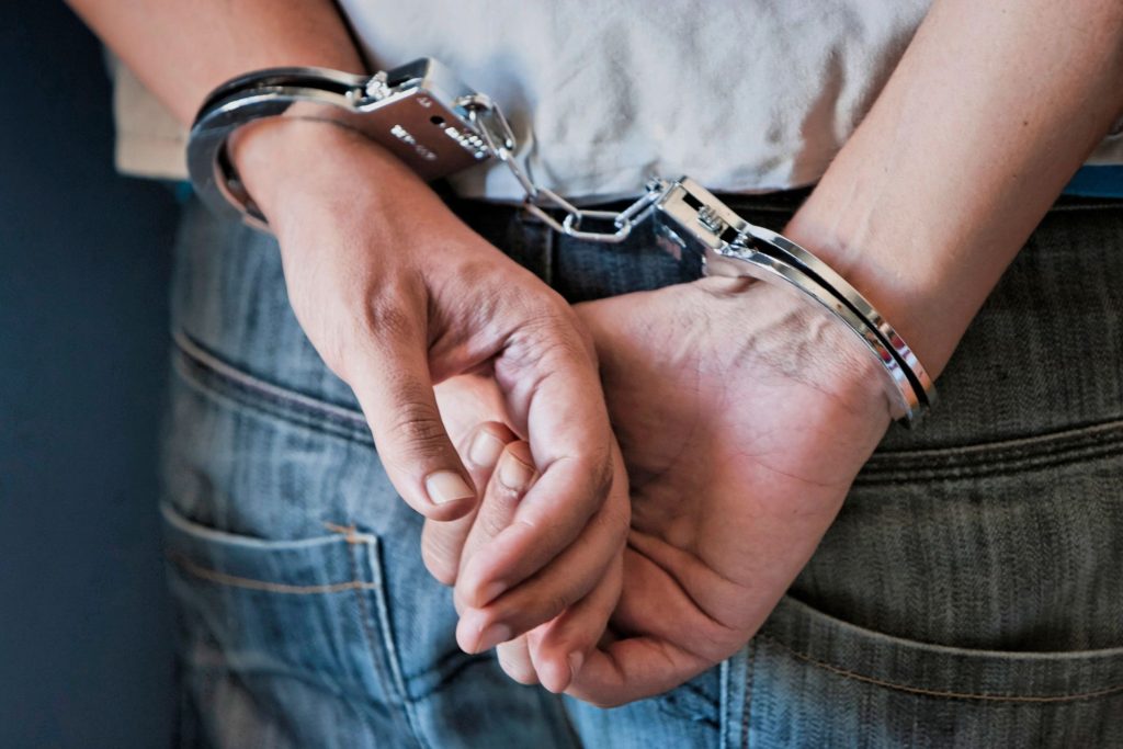 Person with hands cuffed behind back wearing jeans.