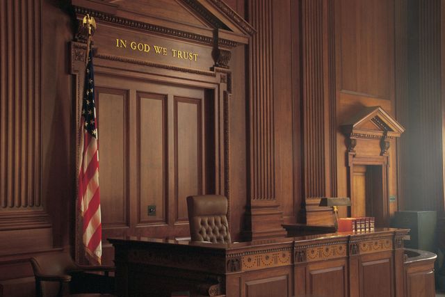 Empty courtroom with judge's bench and American flag.